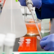 Pipeta de laboratorio científico usando pipeta con bata blanca